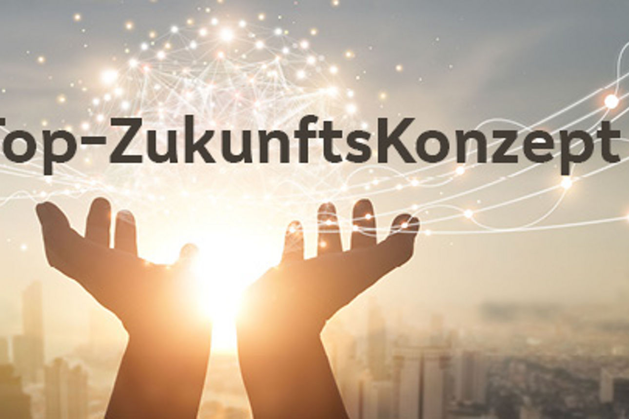 Der Text „VR-Top-ZukunftsKonzept“ ist in grauen Buchstaben geschrieben und zwei Hände halten den Text in ihren Handflächen.
