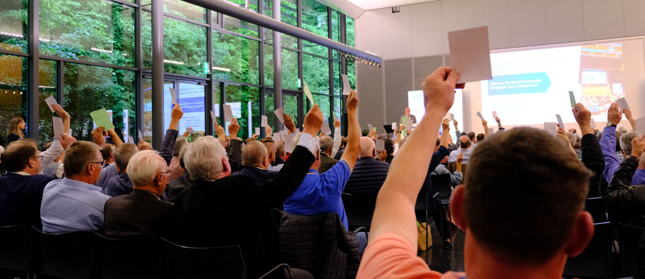 Menschen auf einer Versammlung, die Stimmzettel hochhalten