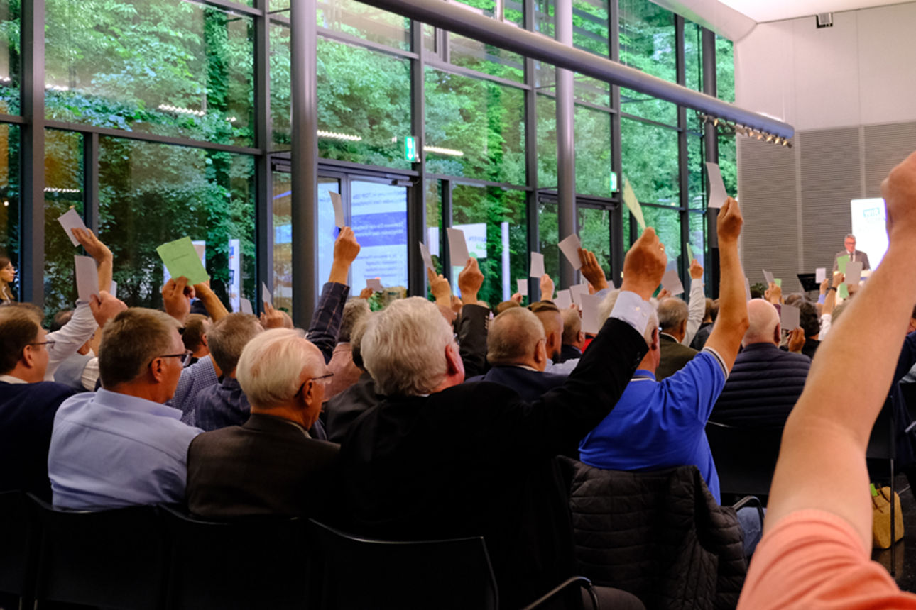Menschen auf einer Versammlung, die Stimmzettel hochhalten