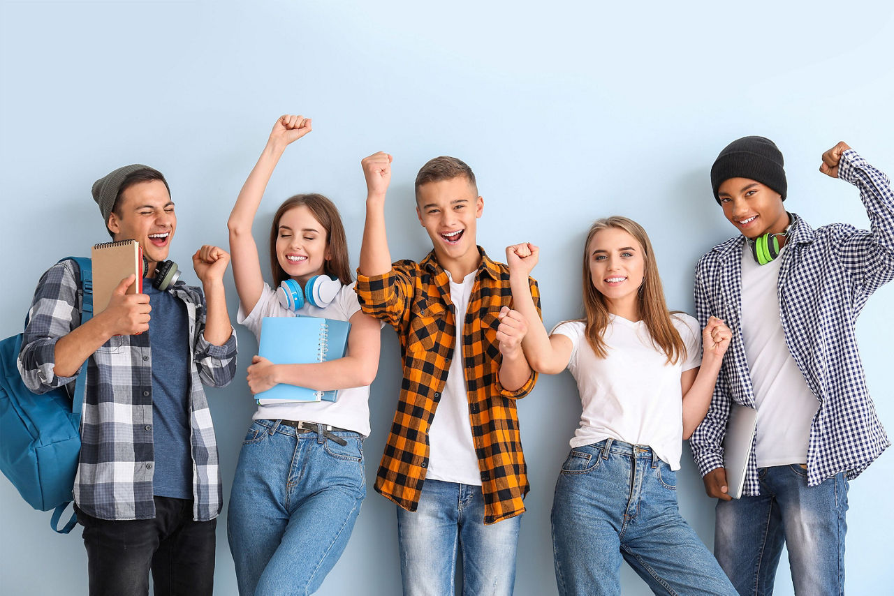 Fünf Schüler stehen vor einer Wand und jubeln