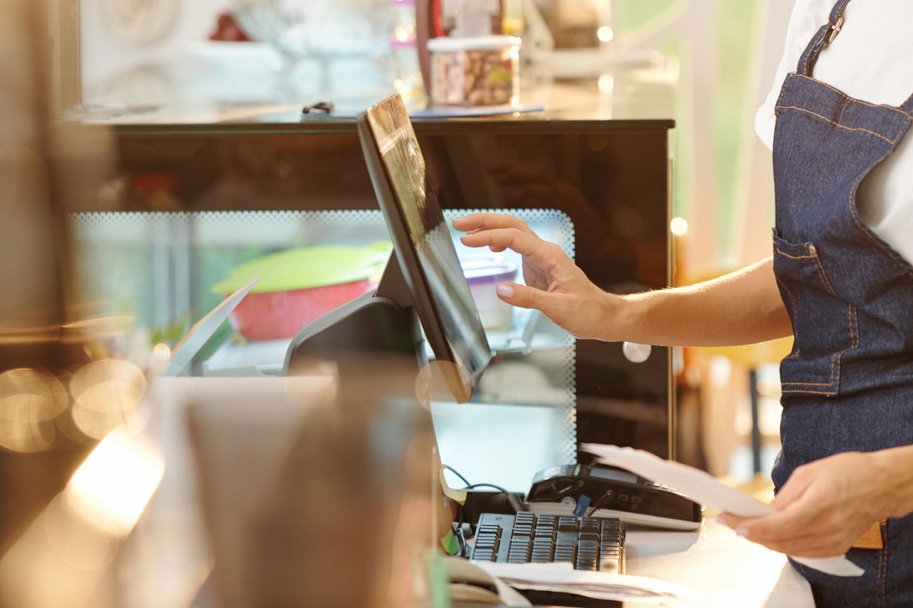 Person tippt etwas in die Computerkasse ein.