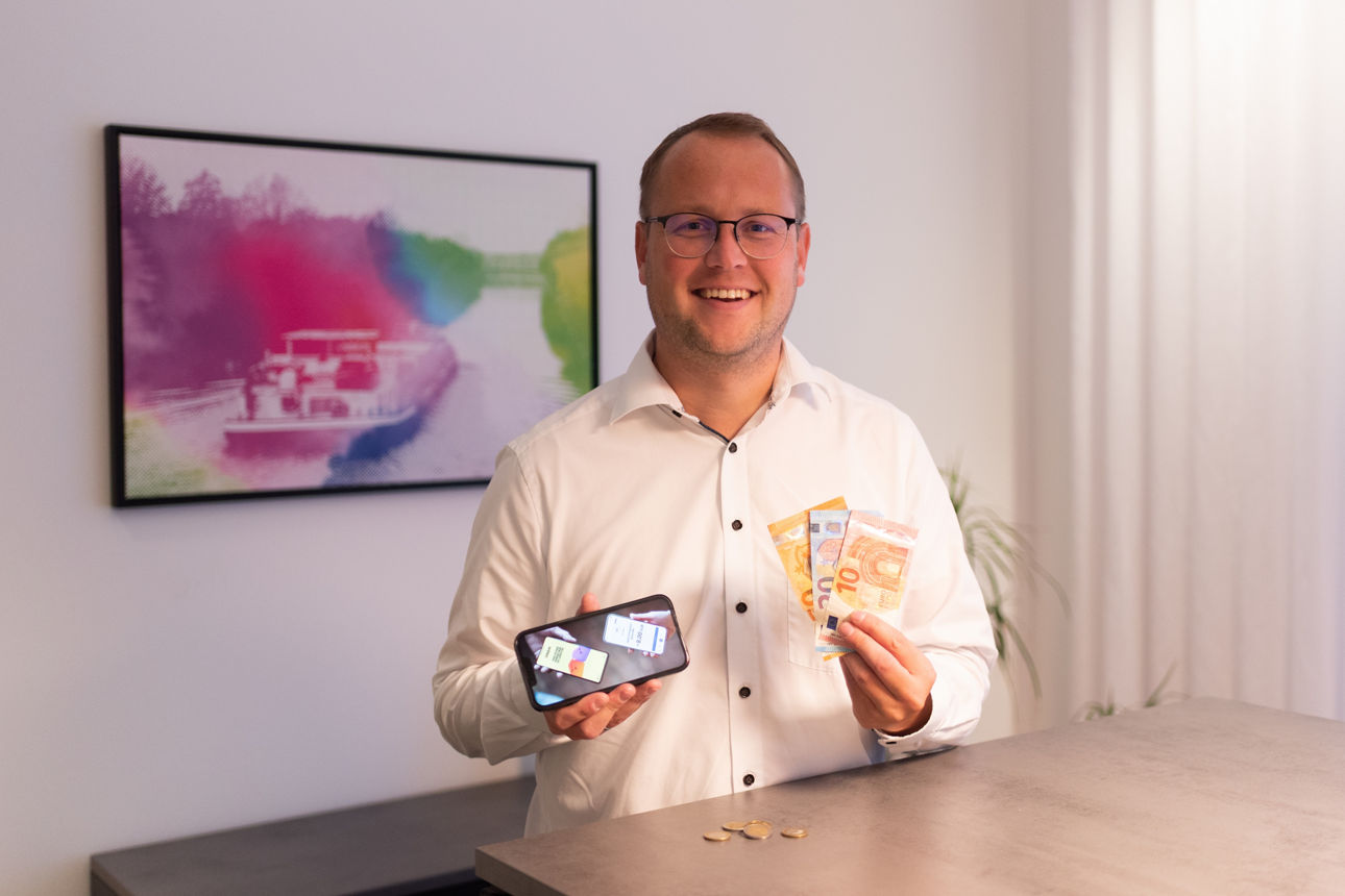 Mitarbeiter mit Bargeld und Handy in der Hand