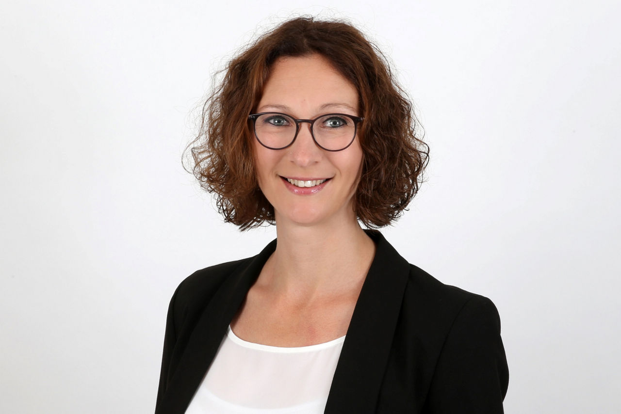 Eine lächelnder Frau schaut in die Kamera.