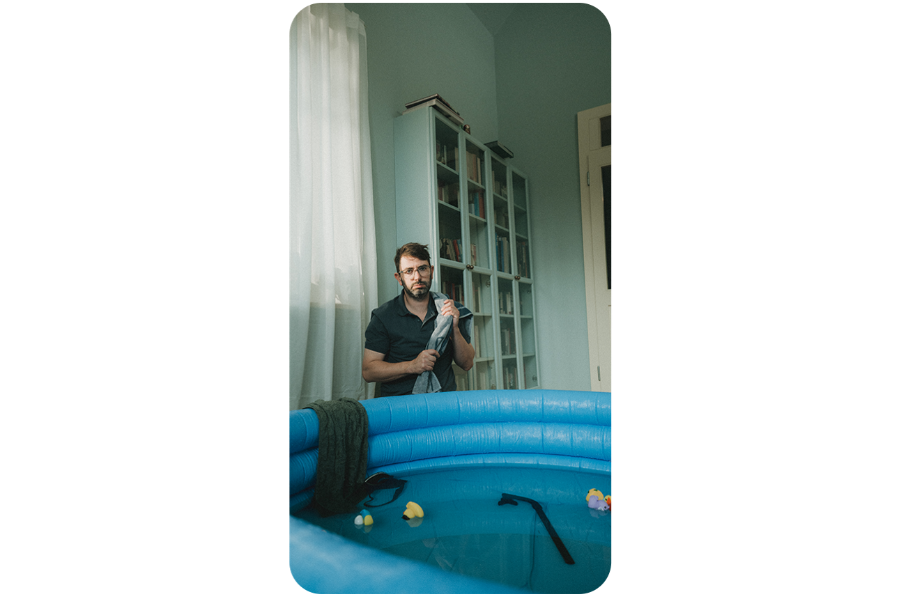 Ein Mann kniet in seinem Wohnzimmer vor einem Pool.