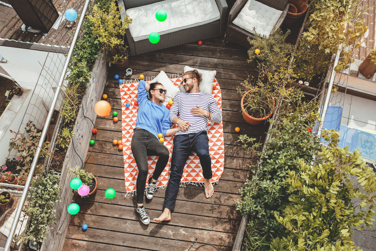 Junges Pärchen liegt auf der Dachterrasse auf einer Decke