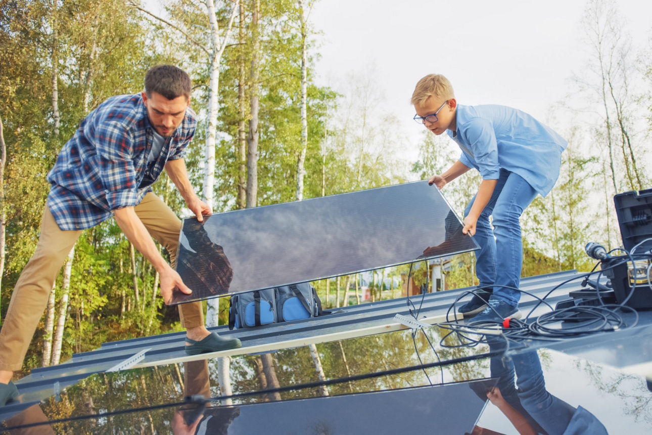 Vater und Sohn bringen Solarmodul auf Dach an