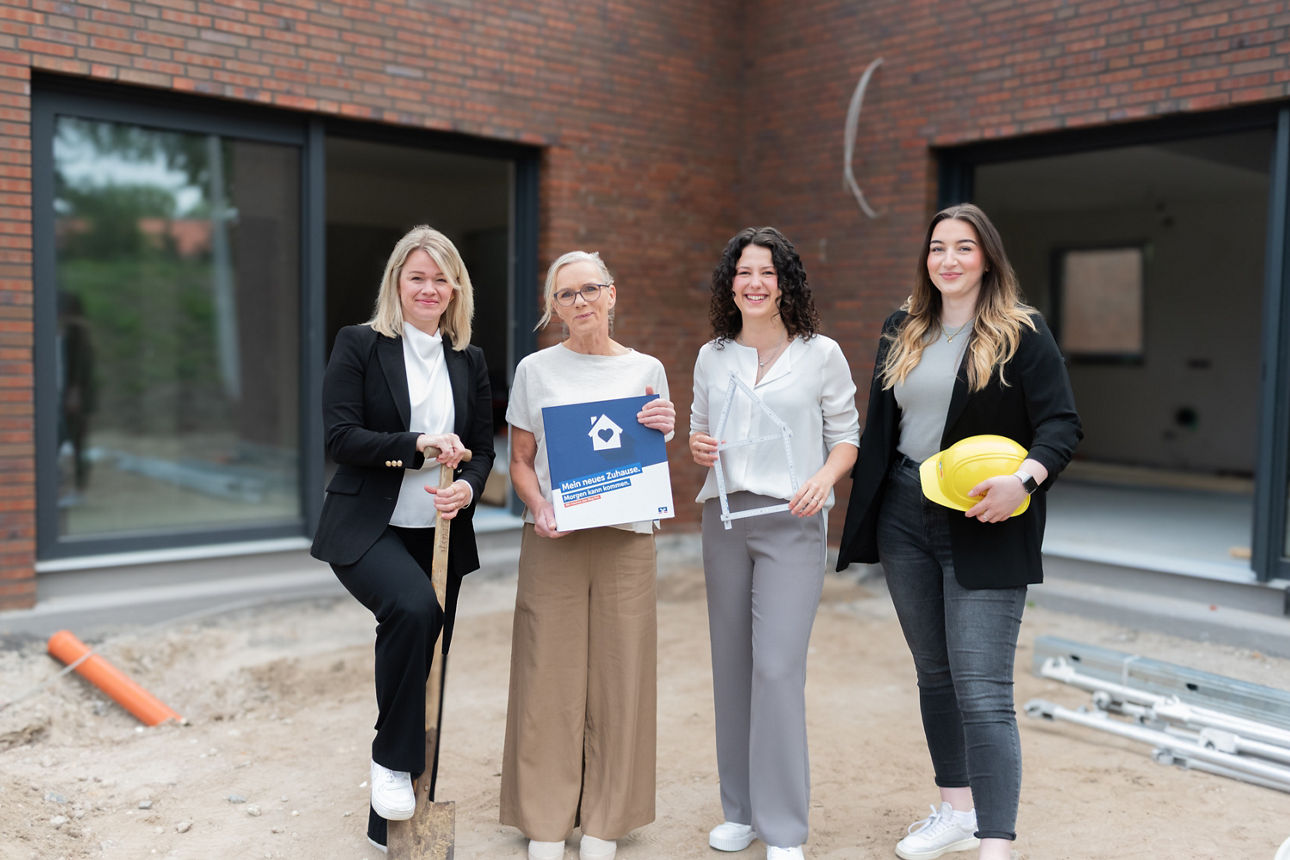 Vier Frauen stehen vor einem Neubauobjekt. 