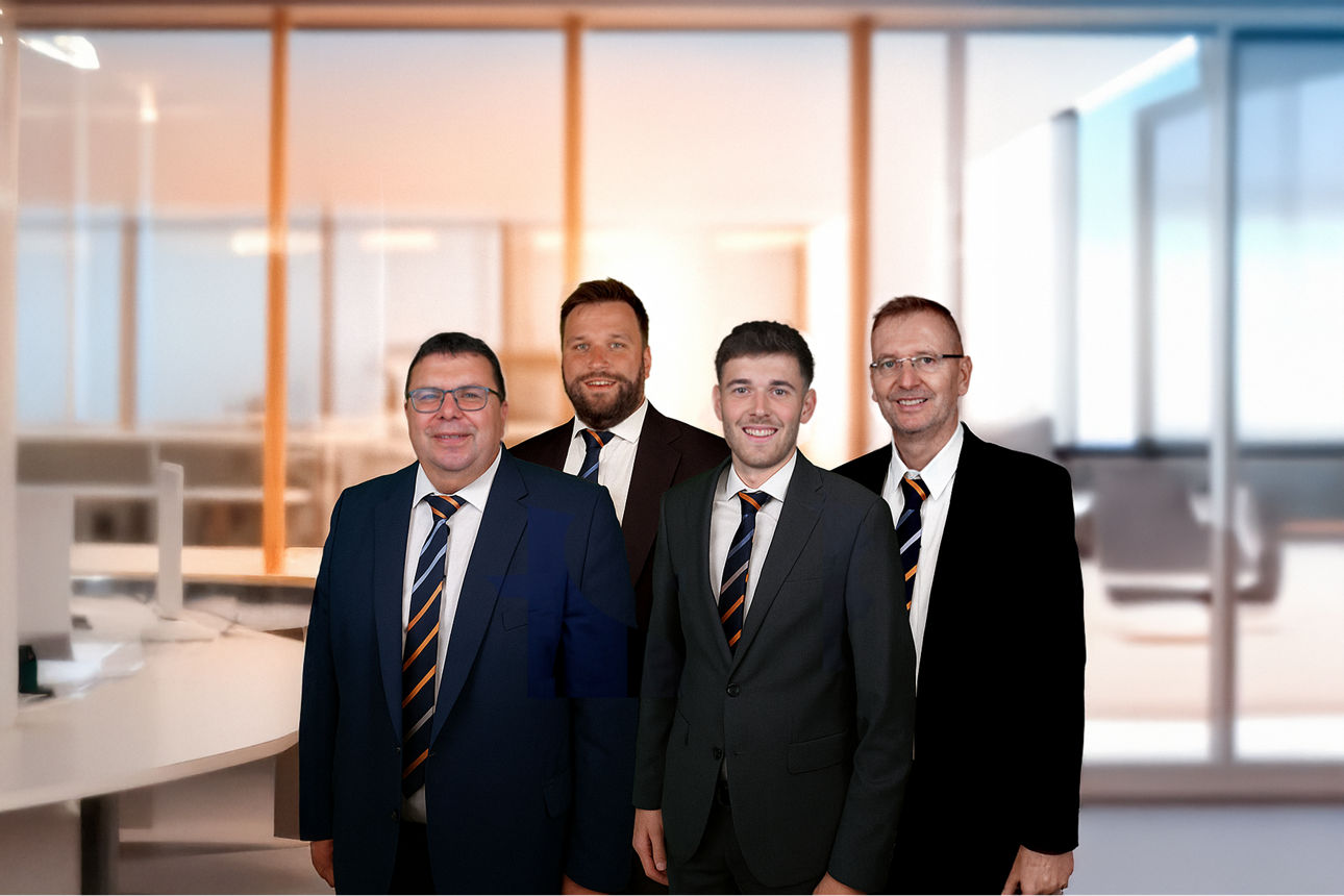 Gruppenbild mit vier Männern mit Anzug und Krawatte