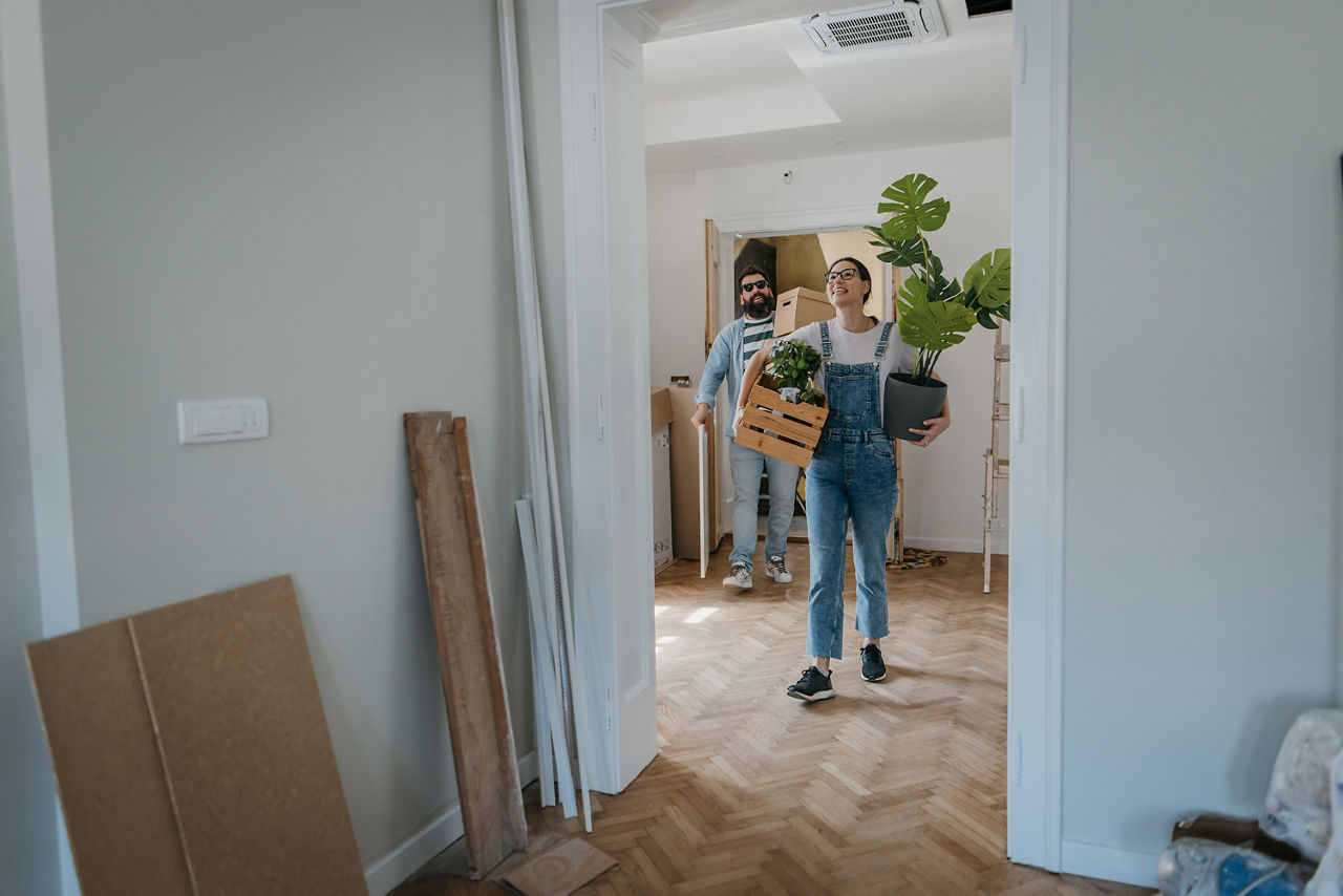 Ein Paar betritt mit Kisten im Arm, die neue Wohnung.