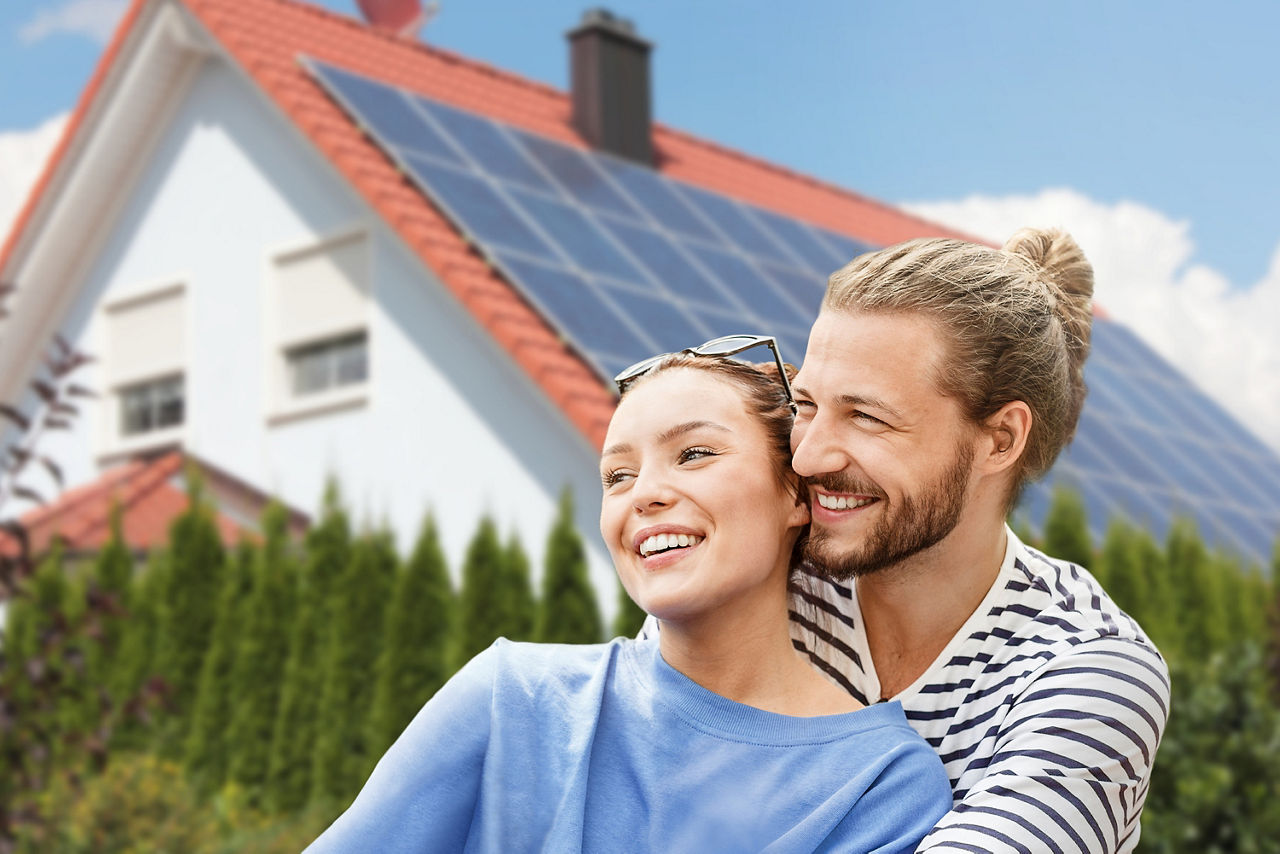 Ein junges Paar steht glücklich vor einem Haus