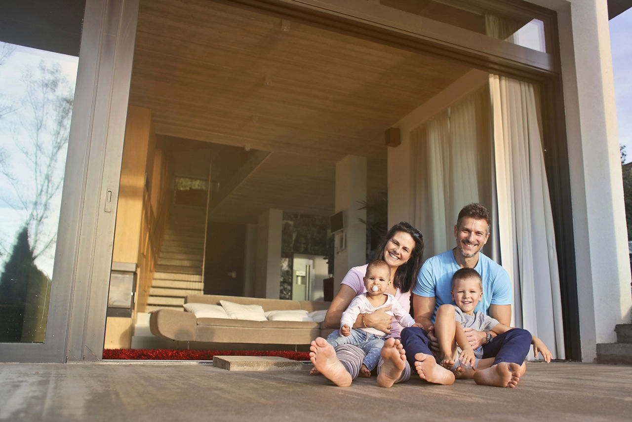 Ein paar mit zwei kleinen Kindern sitzt auf der Veranda ihres Eigenheims