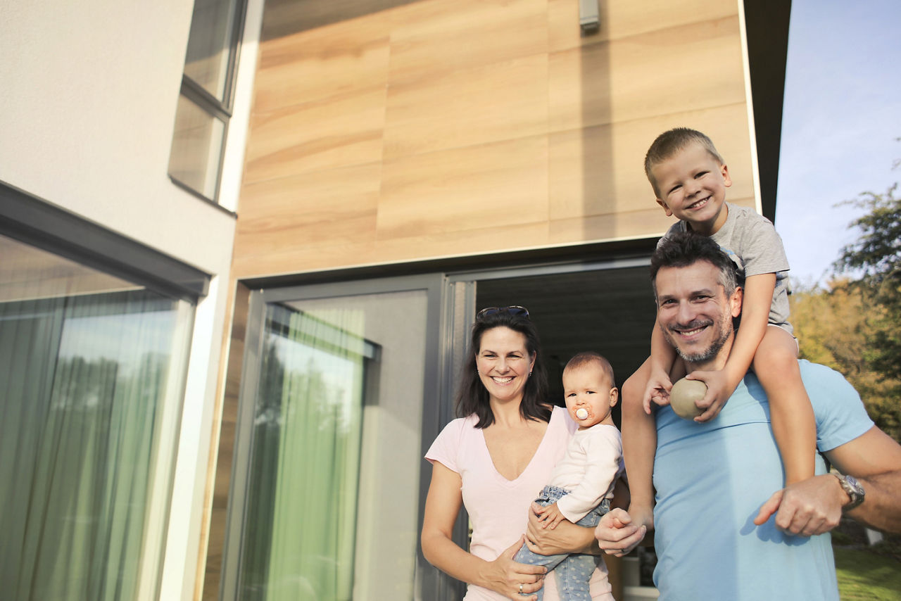 Familien-Portrait von einem Paar mit zwei Kindern vor ihrem Haus.