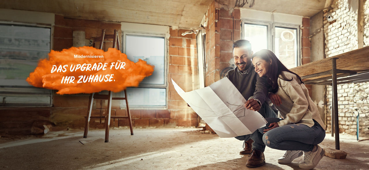 Junges Paar befinden sich in einer hockenden Position im Rohbau einer Wohnung und halten einen Bauplan in den Händen. Links im Bild steht auf einer orangenen Fläche "Modernisieren: Das Upgrade für Ihr Zuhause."