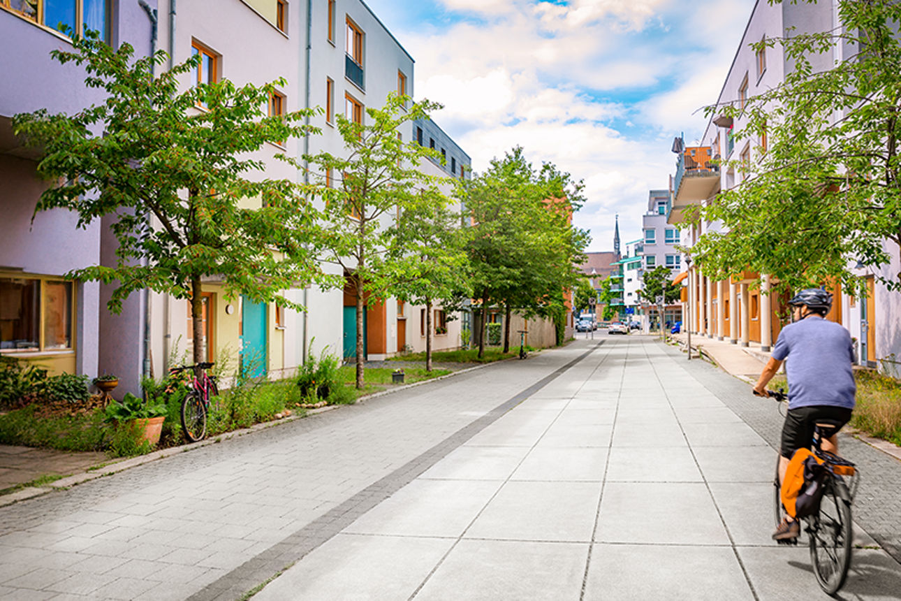 Mann fährt mit einem Fahhrad durch ein Wohngebiet