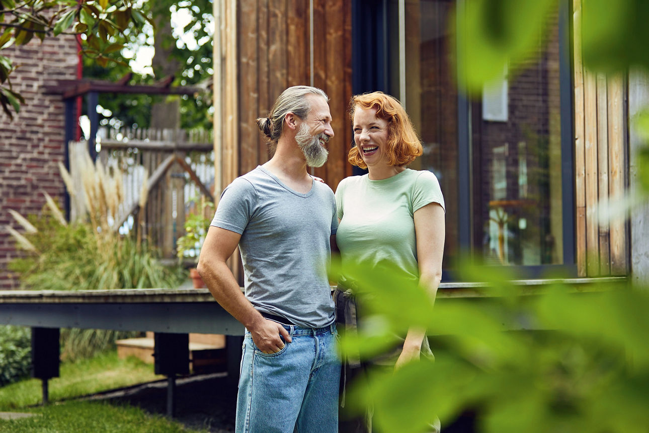 Mann und Frau stehen lächelnd in einem Garten