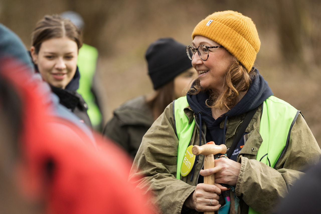 Zwei Mitarbeiterinnen stehen im Wald bei der Baumpflanzaktion mit Spaten in der Hand und unterhalten sich untereinander.