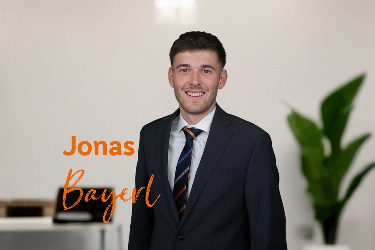 Das Bild zeigt einen Mann in einem Büro mit einem orangen Text "Jonas Bayerl"