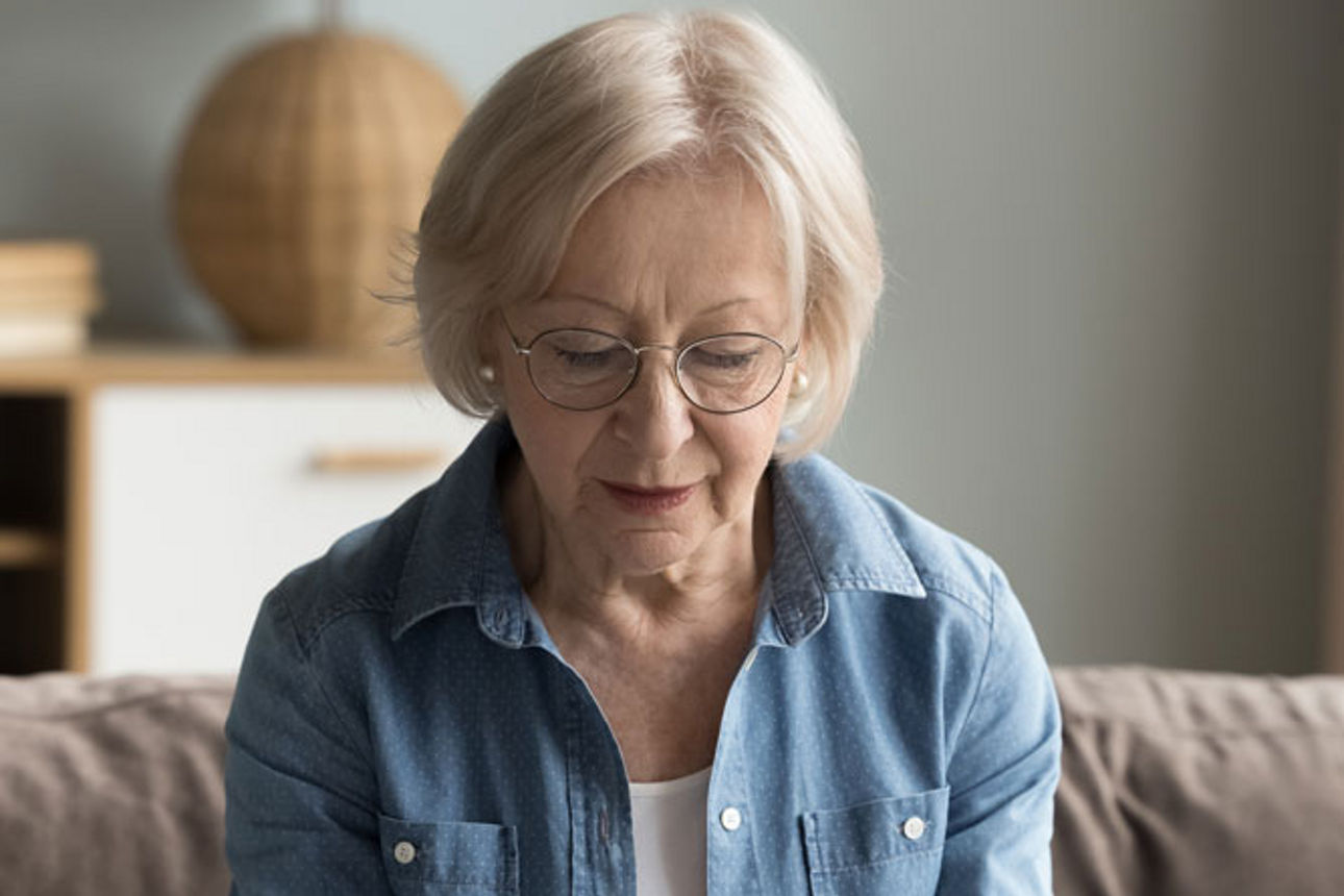 Ältere Frau nutzt Laptop und Taschenrechner, wirkt konzentriert bei Finanzplanung.