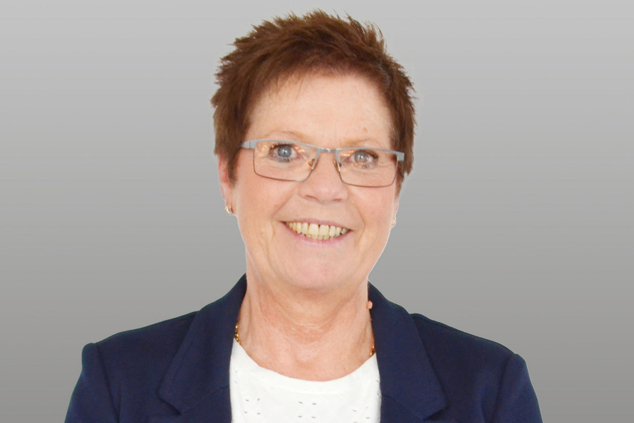 Servicemitarbeiterin Anke Belzer vor grauen Hintergrund