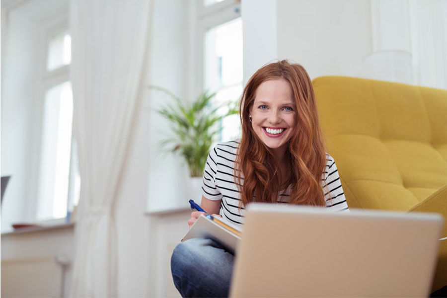 Frau sitzt mit Laptop auf Sofa und lernt