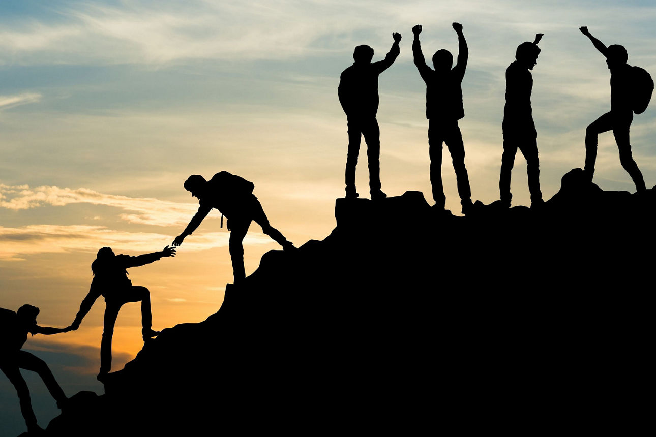 Silhouetten von Bergsteigern, die einen gemeinsamen Sieg feiern.
