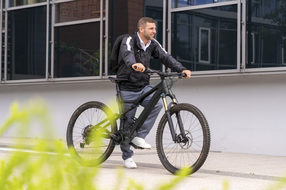 Mann steht mit seinem Fahrrad vor einem Gebäude