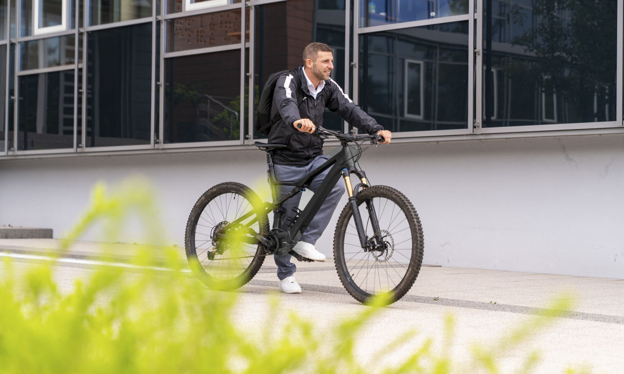 Mann steht mit seinem Fahrrad vor einem Gebäude