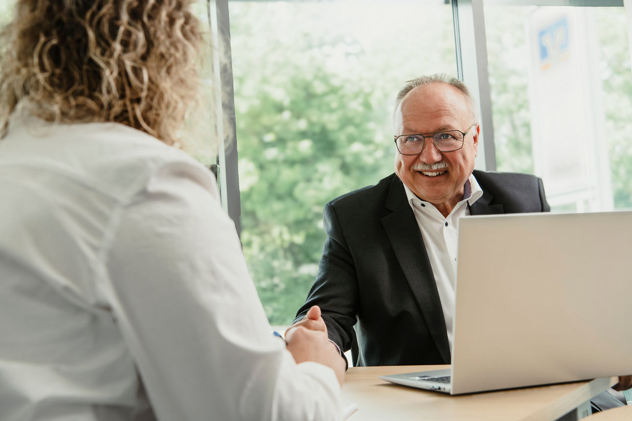 Mann mit Laptop und Rückseite einer Frau in einem Beratungszimmer