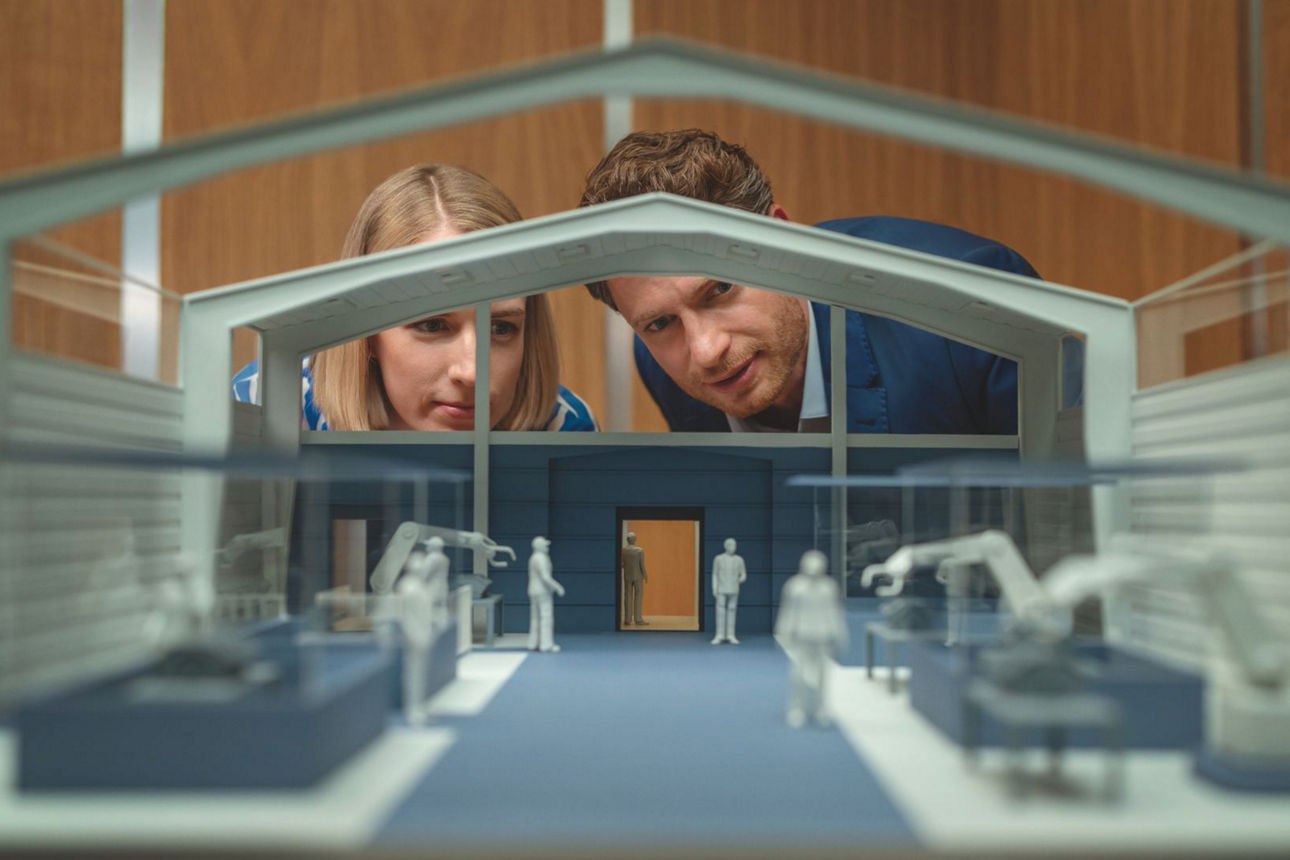 Mann und Frau betrachten Modell einer Werkhalle