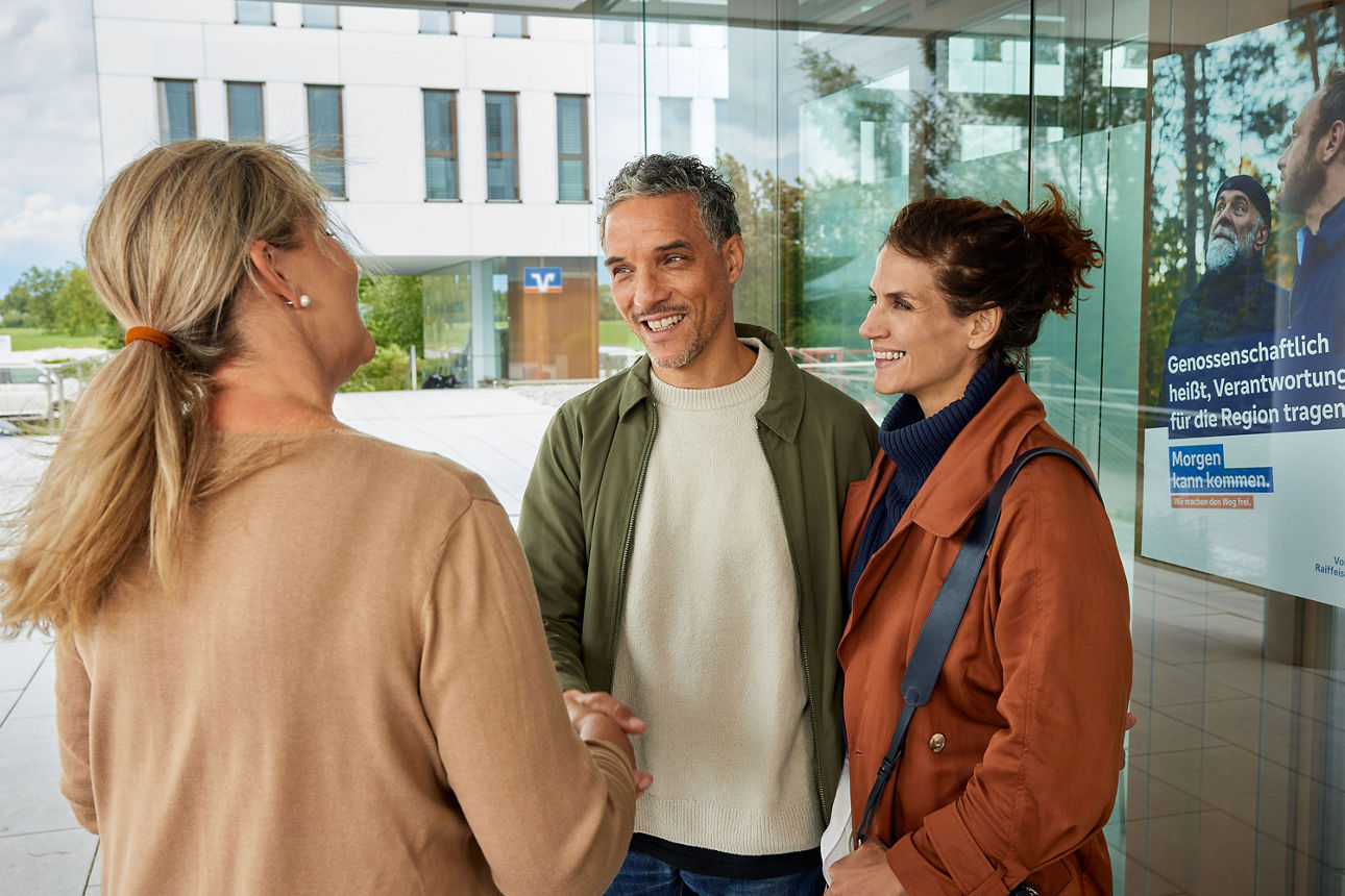 Beraterin begrüßt Paar vor Geschäftsstelle