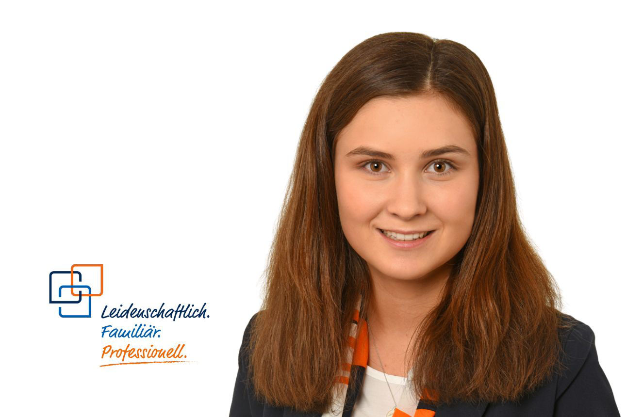 Porträt von Bernadette Huber, einer lächelnden jungen Frau mit langen braunen Haaren. Daneben das Firmenlogo und der Slogan "Leidenschaftlich. Familiär. Professionell."