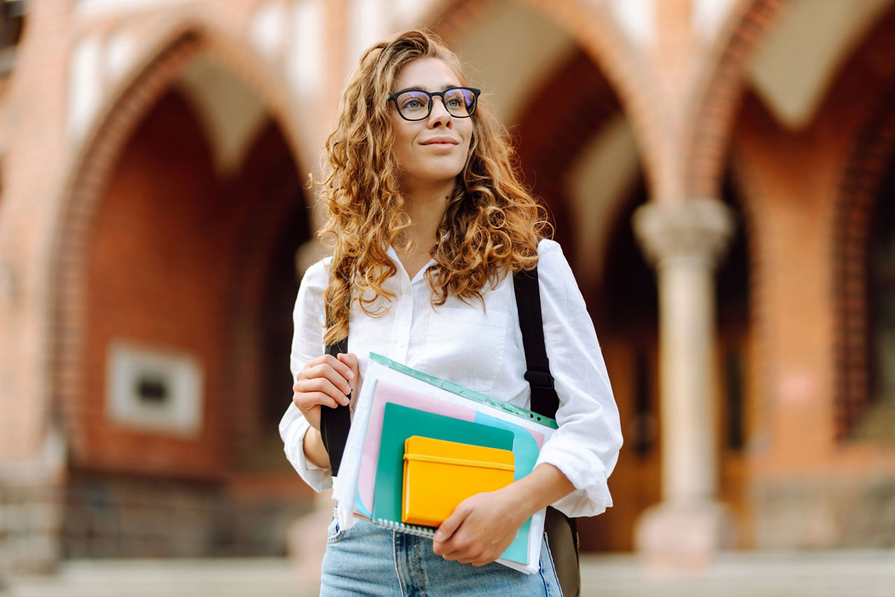 Junge Frau, lachend mit Büchern in der Hand