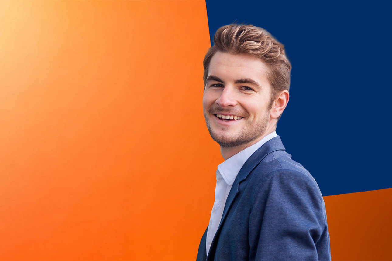 Junger Mann im blauen Anzug vor orange-blauer Wand