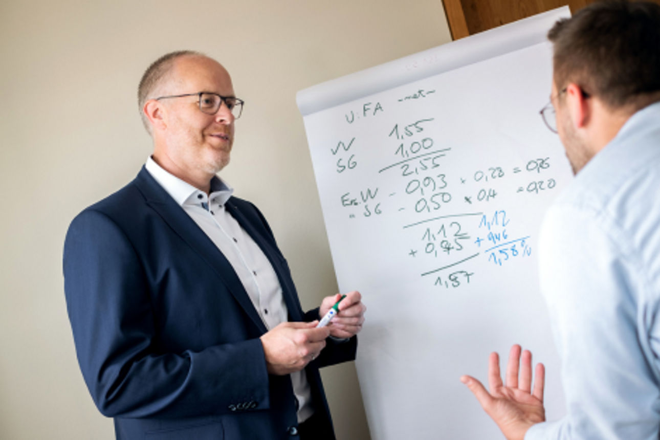 Zwei Männer unterhalten sich vor einen Flipchart