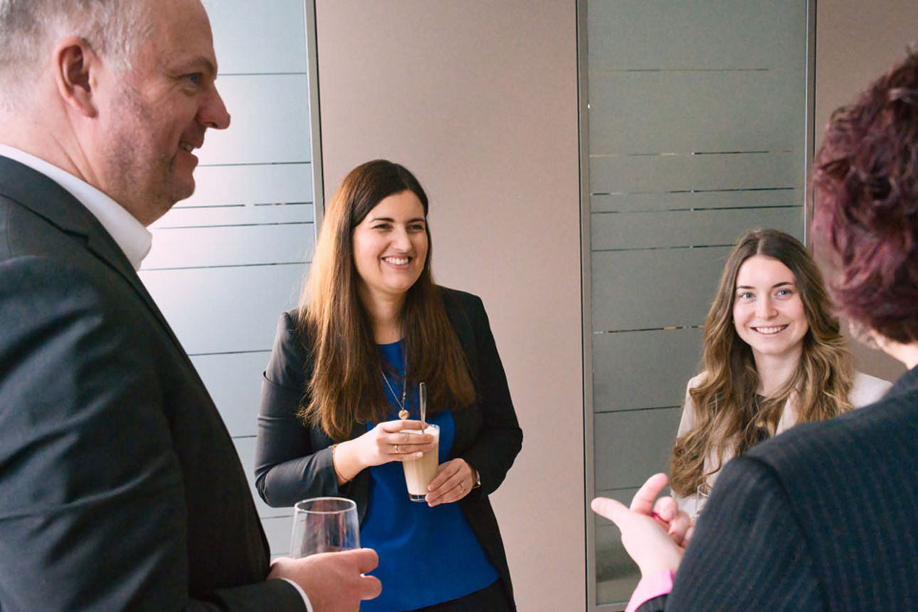 Vier Personen stehen im Kreis und unterhalten sich