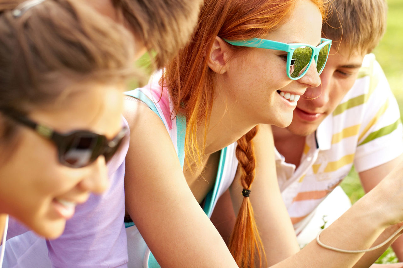 Junge Leute haben Spaß im Sommer und checken ihr Smartphone
