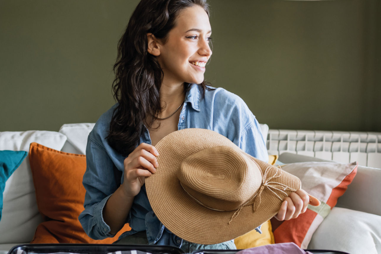 Junge Frau auf Sofa mit Hut in der Hand