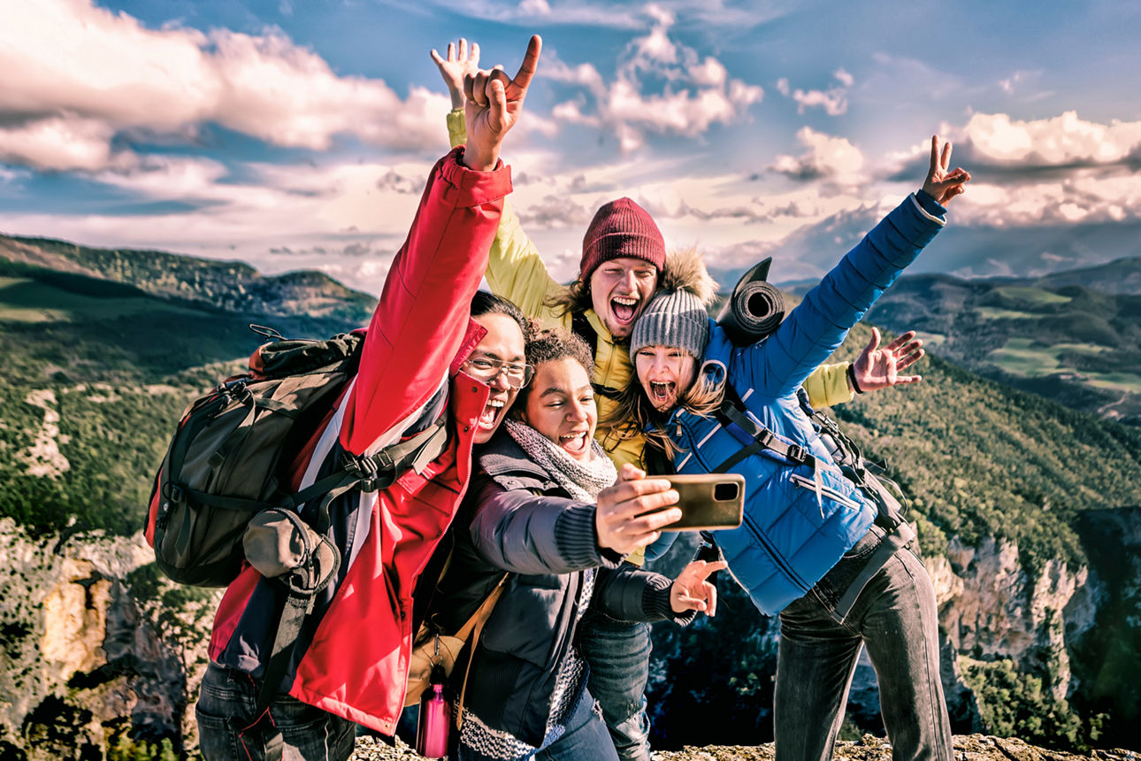 Vier junge Erwachsene stehen auf einem Berg und machen ein Selfie
