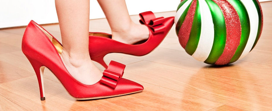 Kinderfuß in roten Pumps kickt gegen weiß, grün, rote Weihnachtskugel