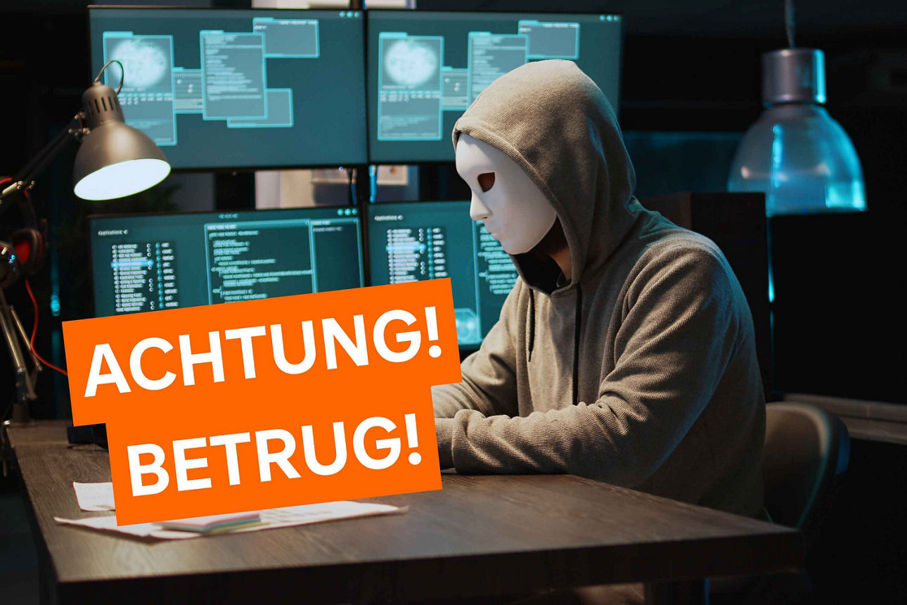 Eine Person mit Maske sitzt vor mehreren Monitoren – Warnhinweis: „Achtung! Betrug!“