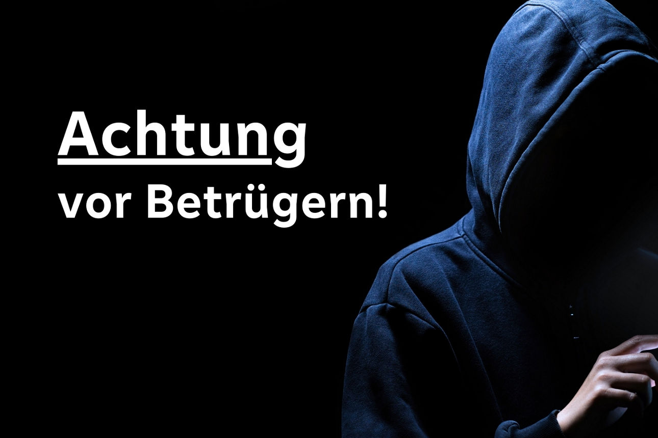 Ein Mann hat sein Gesicht mit einerm Kapuzenpullover verdeckt und tippt auf einem Handy