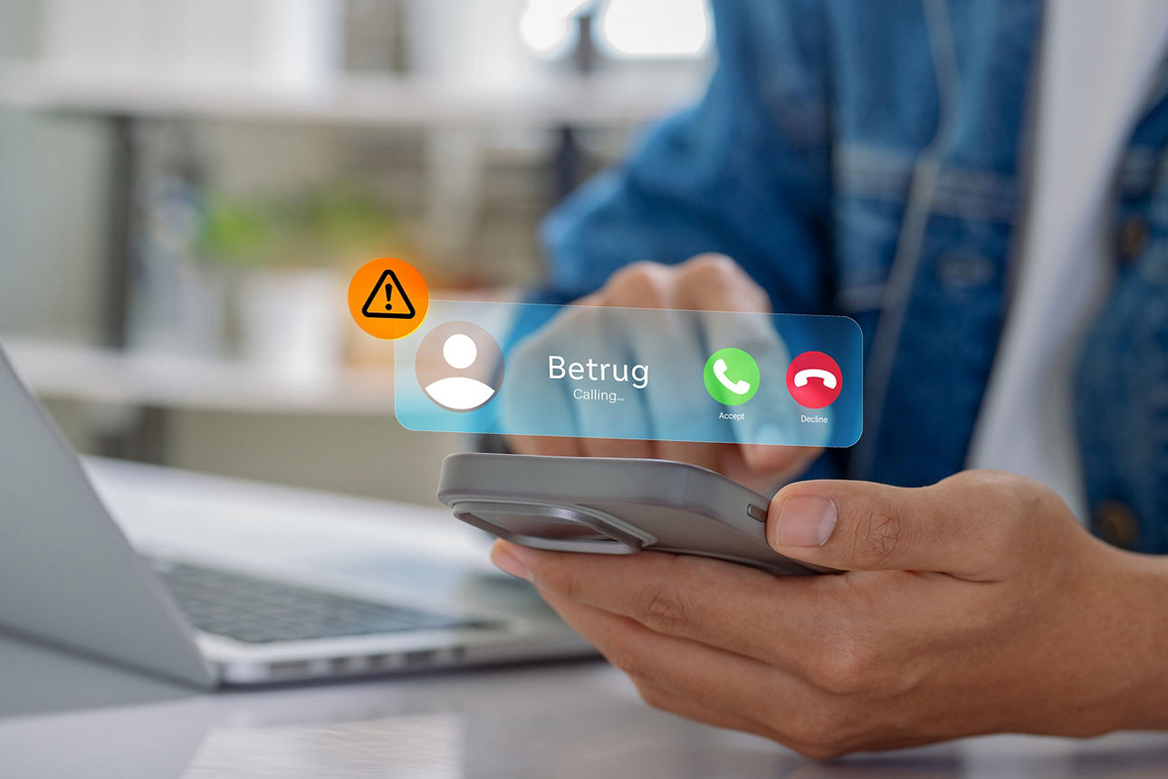 Person hält ein Smartphone; eingeblendeter Anruf mit der Bezeichnung „Betrug“ und Warnsymbol über dem Display.