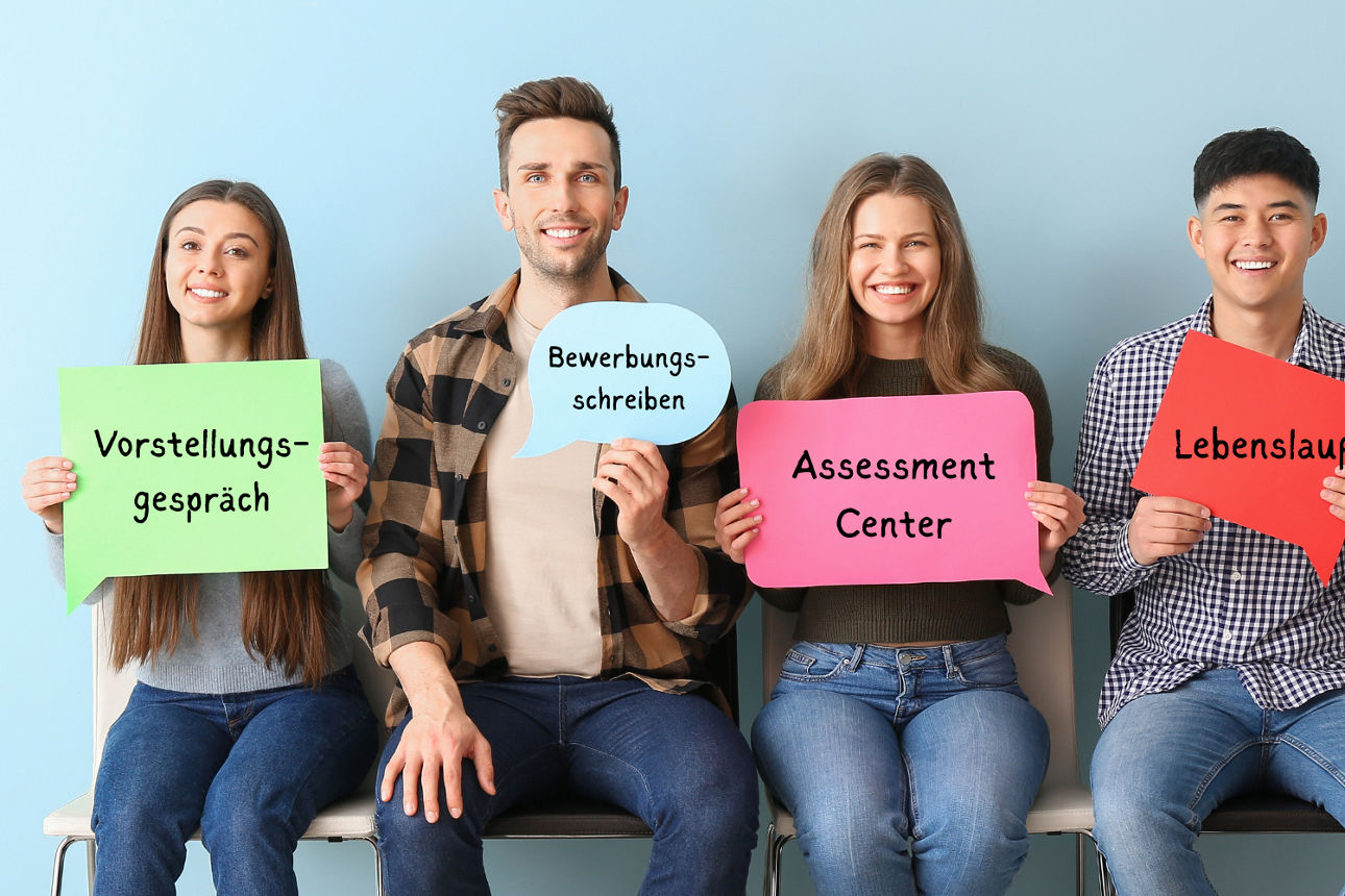 Vier Personen sitzen auf Stühlen und halten bunte Schilder mit den Worten: Vorstellungsgespräch, Bewerbungsschreiben, Assessm