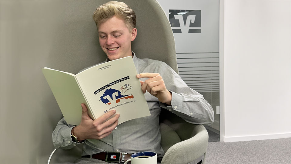 Porträt eines lächelnden jungen Mannes mit einem Buch