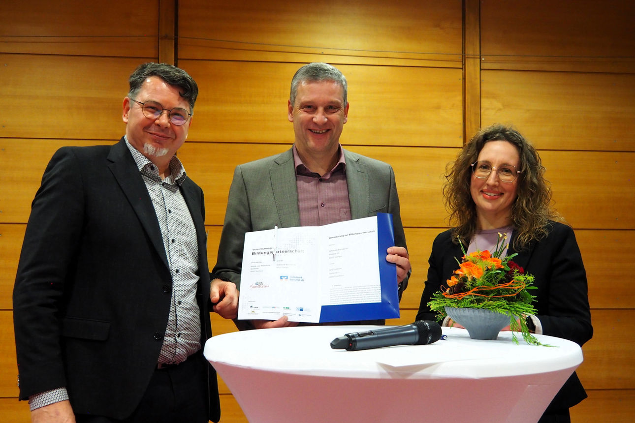 Fünf Personen stehen im Halbkreis, eine Urkunde wird in der Mitte gehalten.