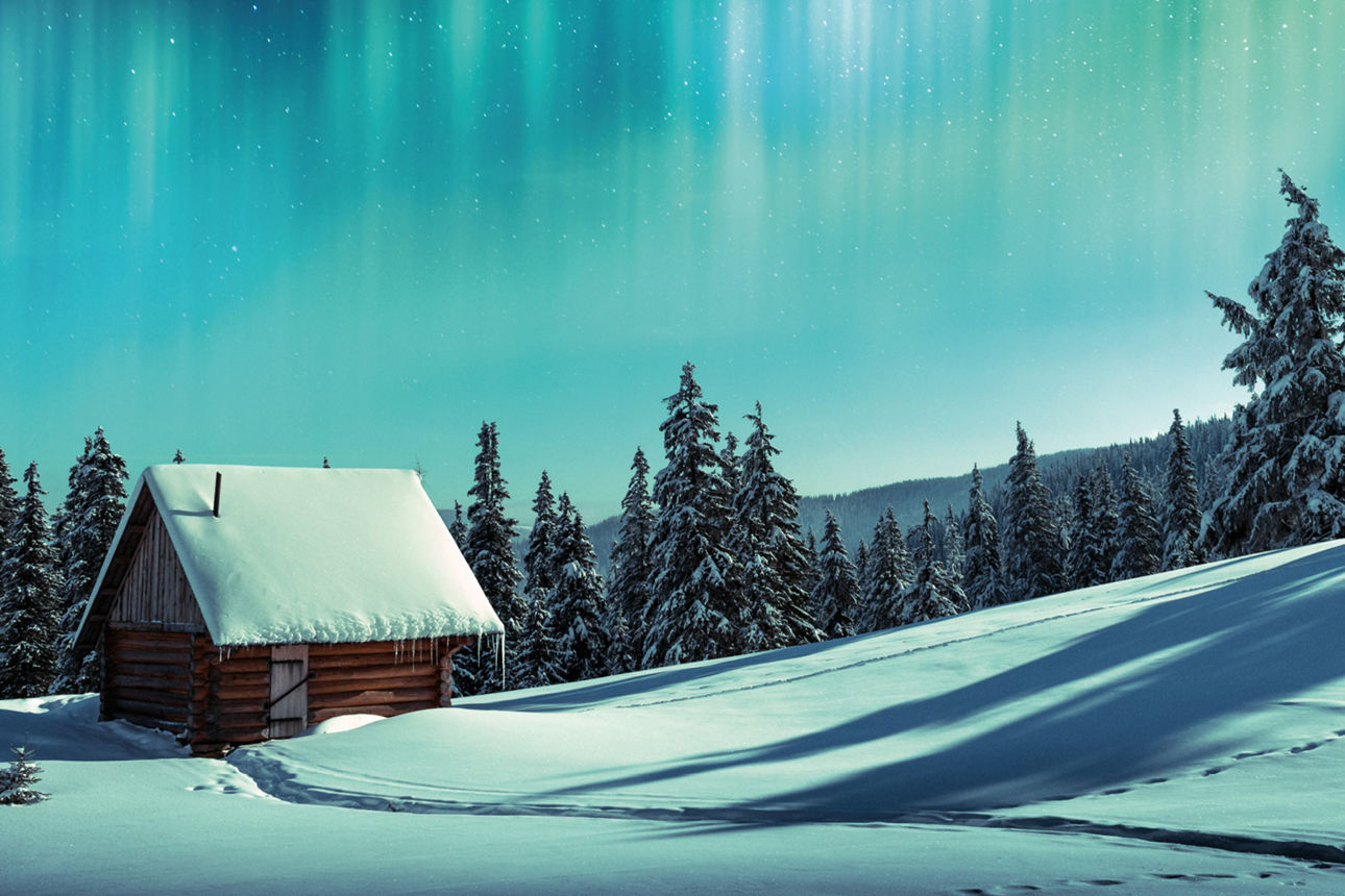 kleine Hütte in verschneiter Landschaft mit den Polarlichtern im Hintergrund