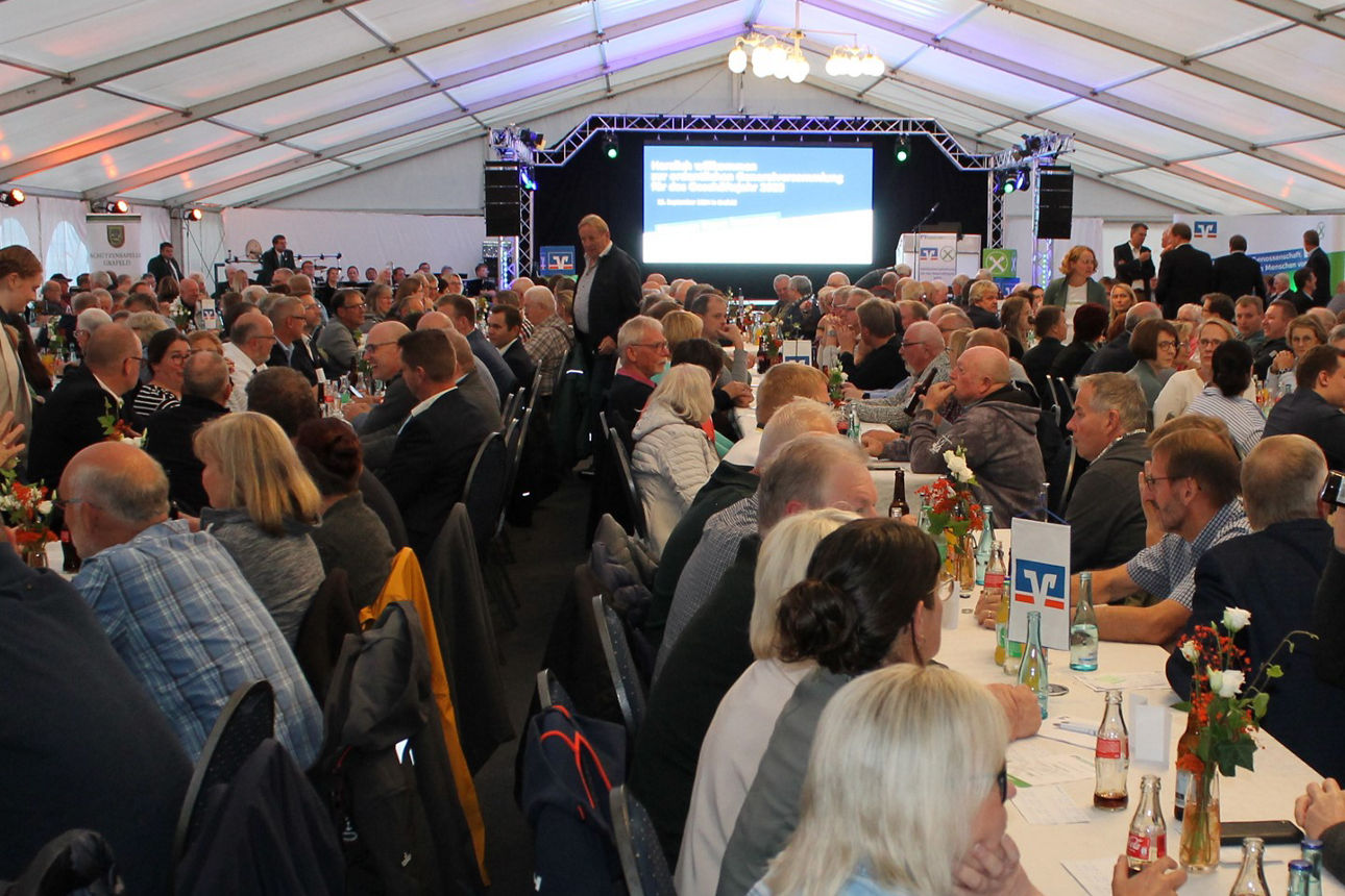 Eine Gruppe von Personen, die an Tischen sitzt, sich unterhält und ihre Zeit in einem geselligen Rahmen genießt.