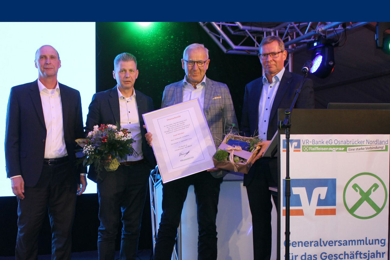 Eine Gruppe von Männern steht vor einem großen Bildschirm, auf dem ein Scheck angezeigt wird, und diskutiert oder feiert.