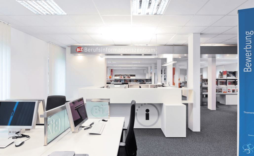 Offener Beratungsbereich einer Bank mit Arbeitsplätzen und Hinweis auf Bewerbungsbereich.