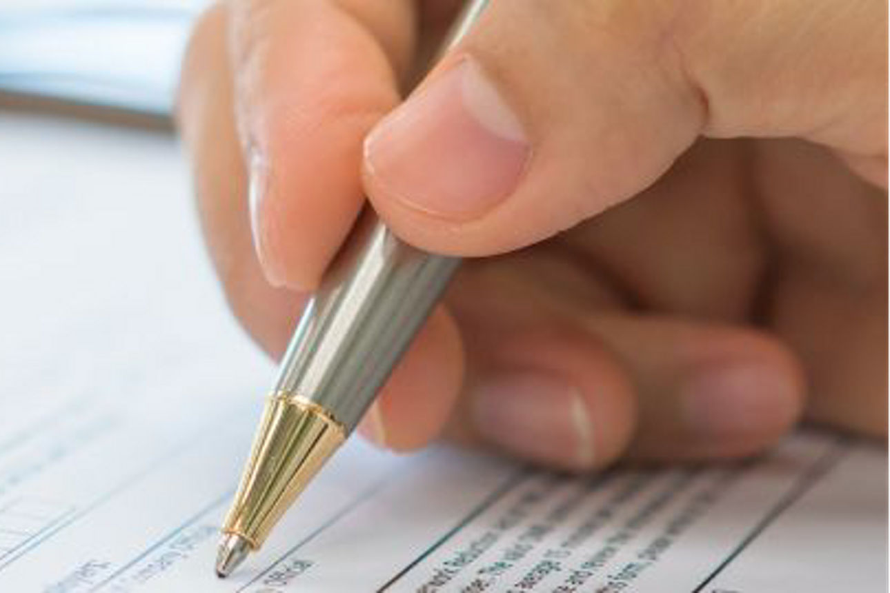 jemand, der einen Stift hält und auf das Papier schreibt